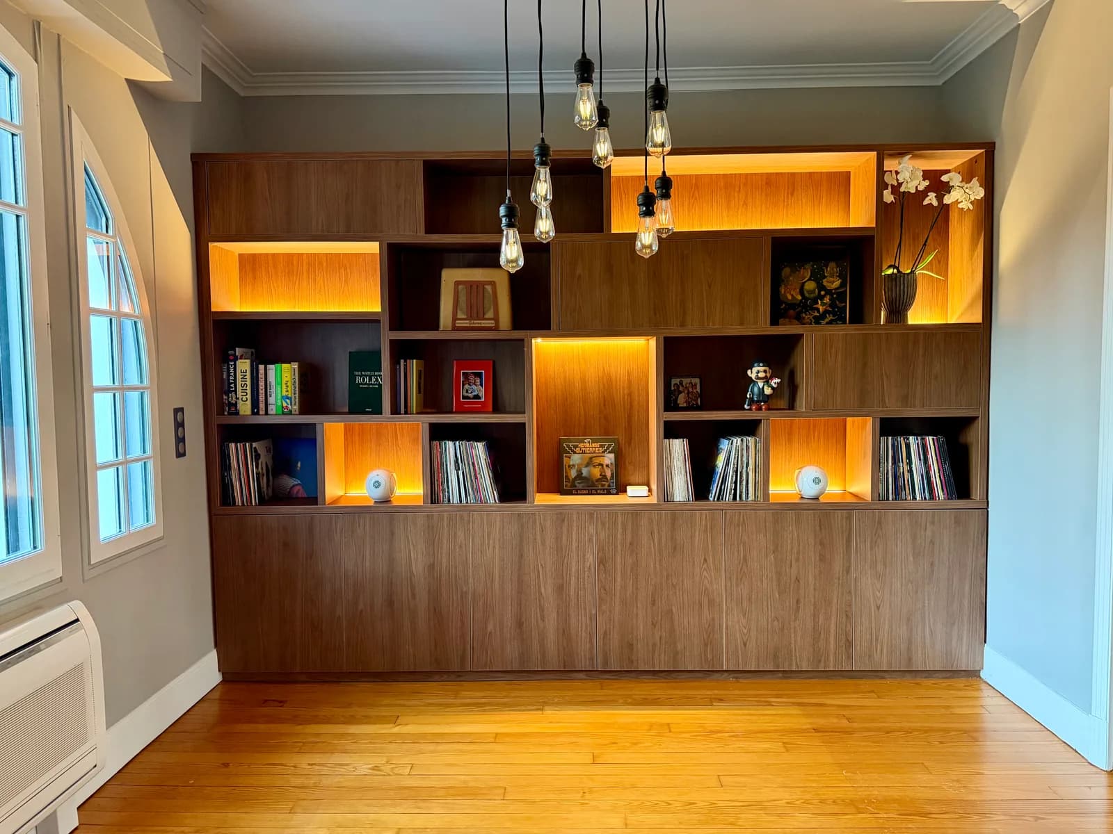 Bibliothèque en noyer sur tout un mur, niches rétroéclairées et rangement bas fermé