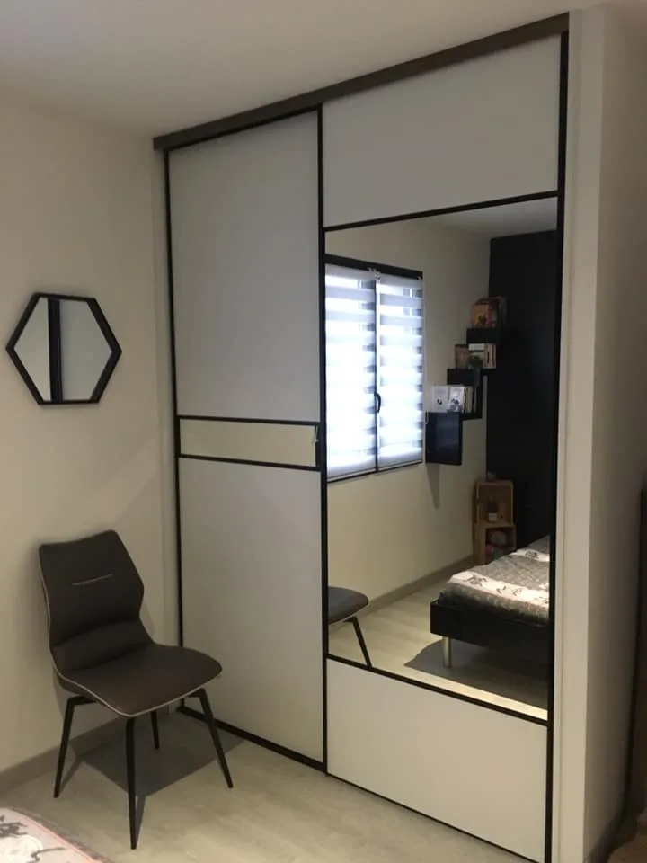 Portes coulissantes blanches à cadre noir et panneau miroir, sur toute la largeur du mur