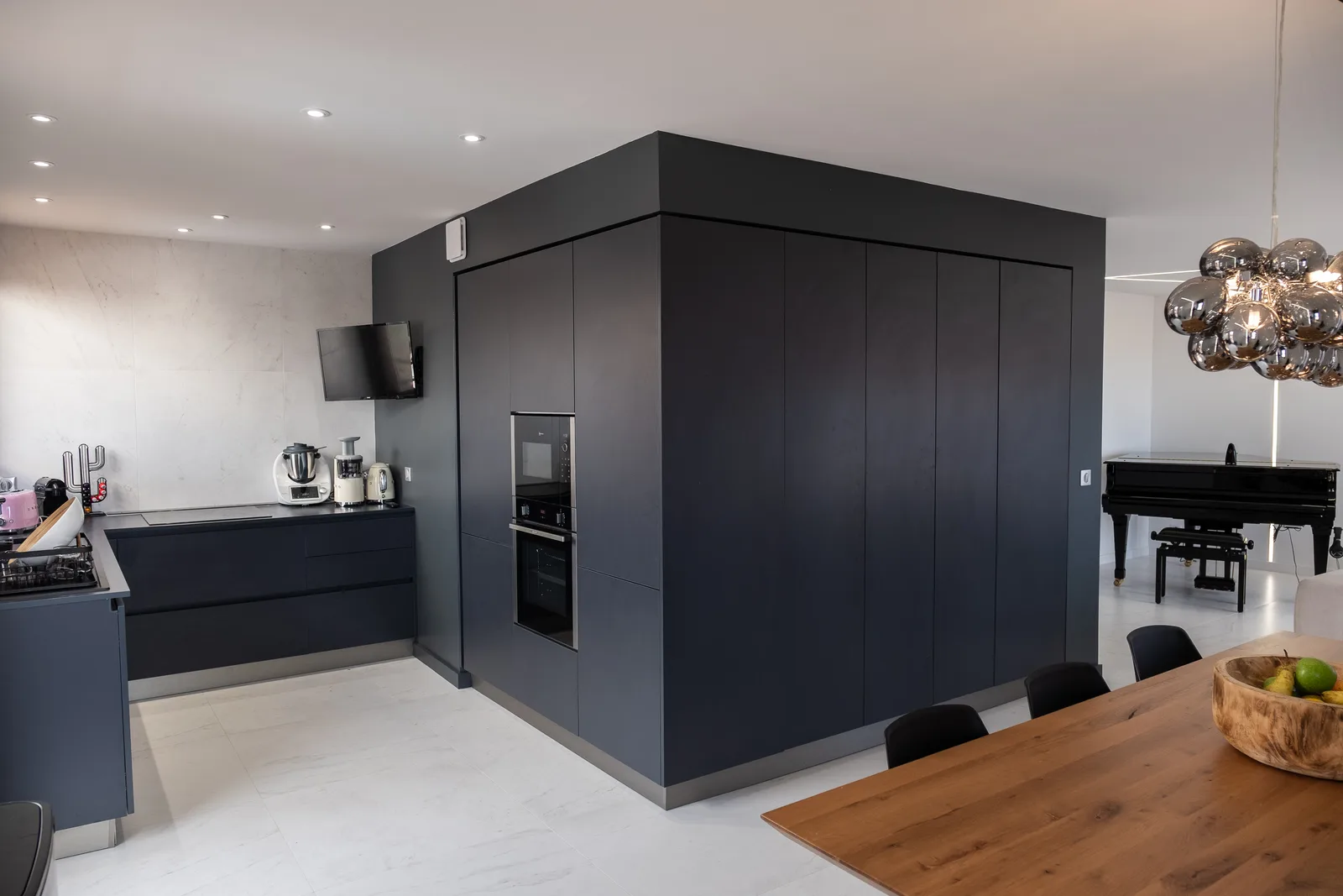 Volume de rangement noir mat toute hauteur, posé entre la cuisine et le séjour
